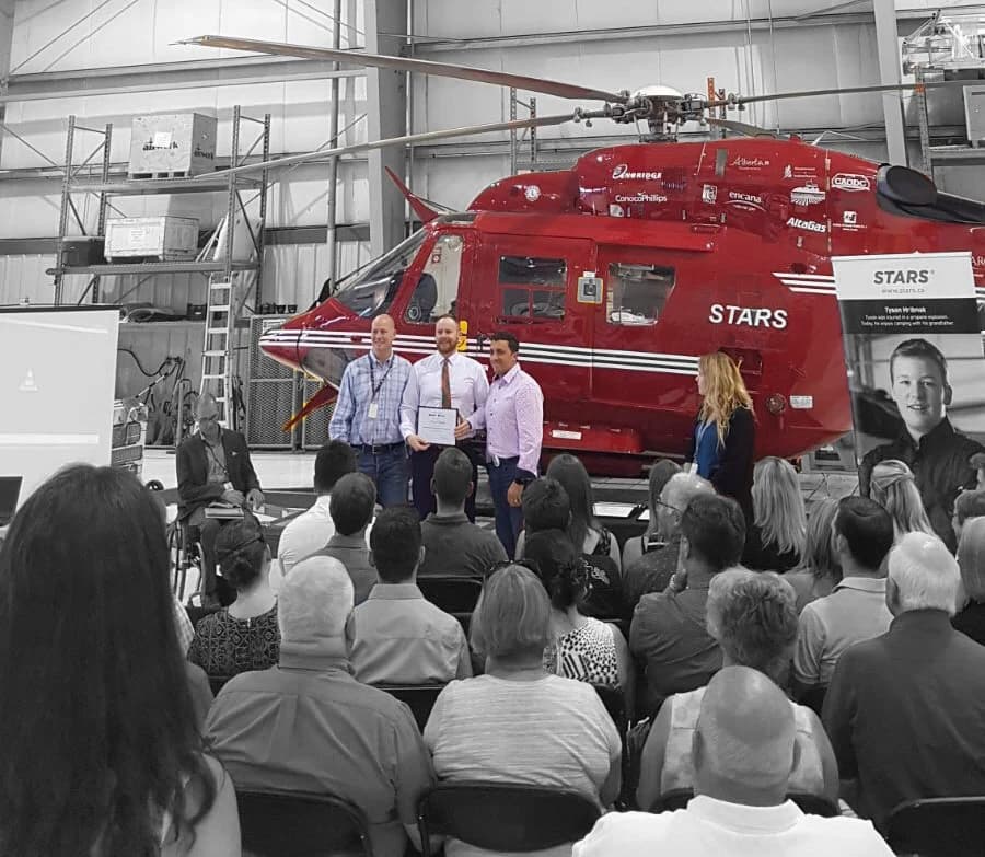 A certificate presentation in front of a STARS air ambulance in its hangar