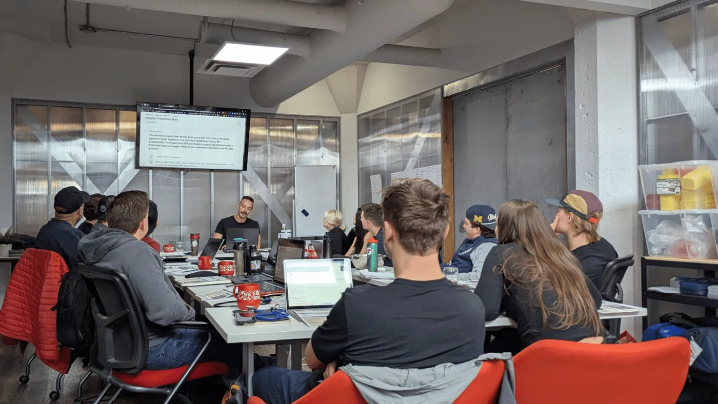 Students at laptops in a Delta classroom, facing the instructor at the front of the room