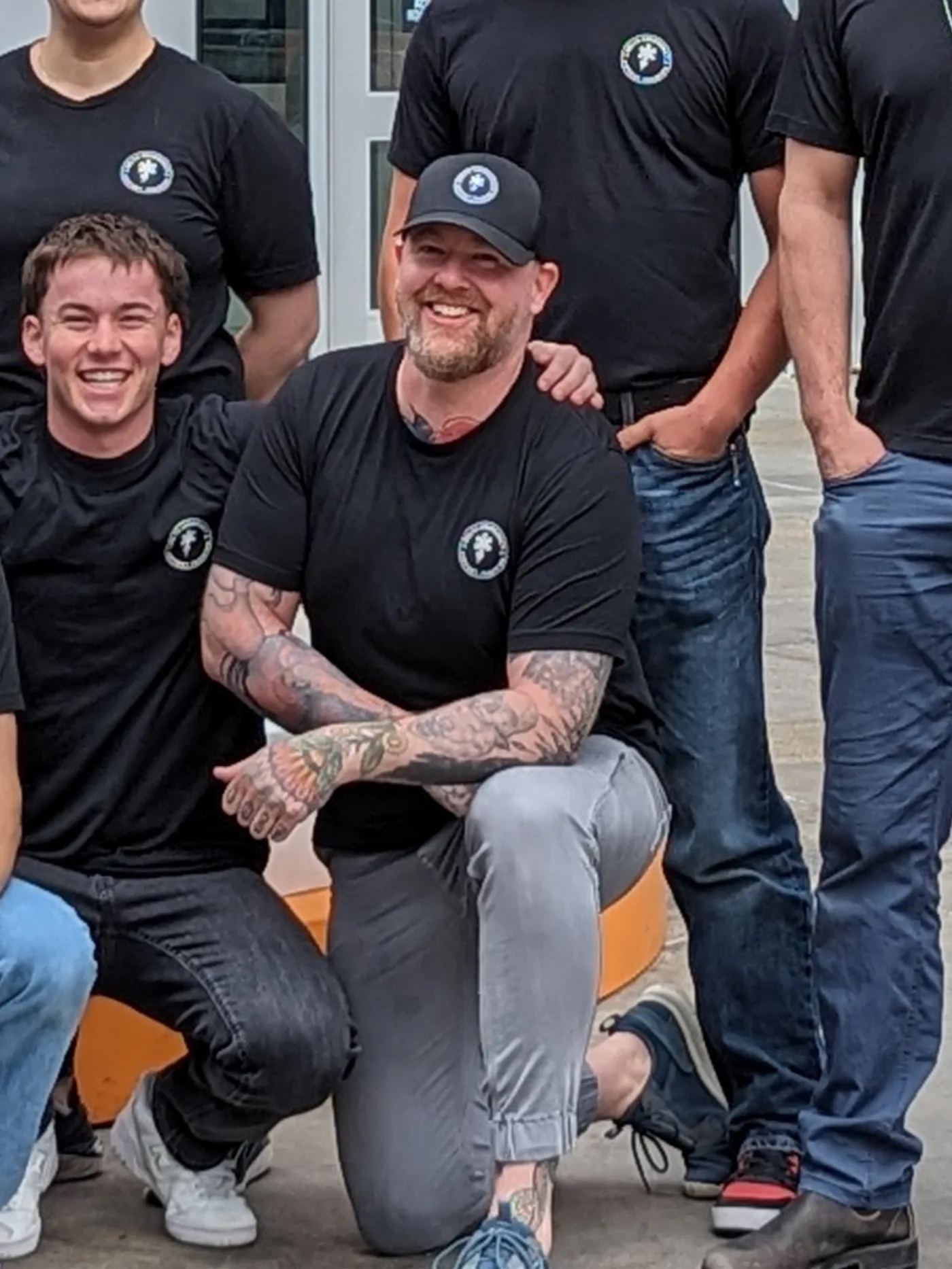 Jarrett Chisholm in a Delta cap, crouched beside a smiling student, with the team standing behind them