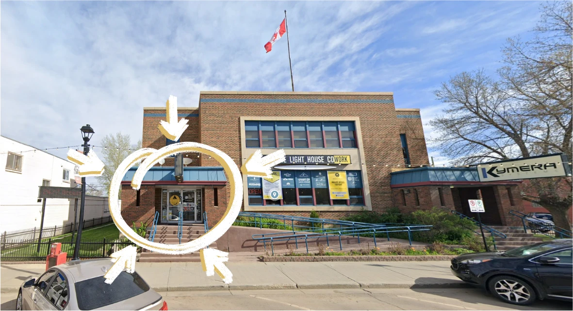 The Light House Cowork building in Leduc, seen from the street: brick, with a Canadian flag. The entrance is on the left under the blue awning. A gold circle marks it.